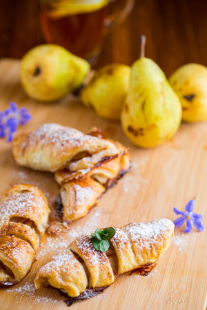 Sweet pastries, puff pastries with pears, on a wooden table.の写真素材