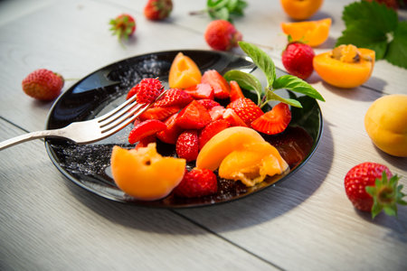 fresh fruit salad of ripe strawberries and apricots, on a light wooden table.の写真素材