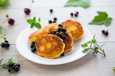 Fried curd cheese pancakes with black currants, on a wooden table.の写真素材