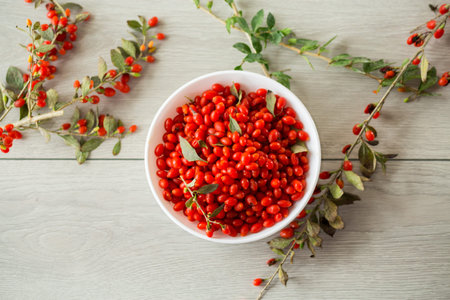 fresh ripe red goji berries in a bowl on a wooden table.