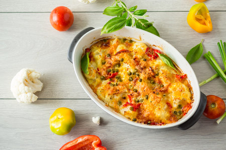 cauliflower baked with sweet pepper and vegetables under cheese, in a ceramic baking dishの写真素材