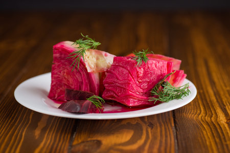 pickled cabbage with beets and carrots, in a plate, on a wooden table.の写真素材