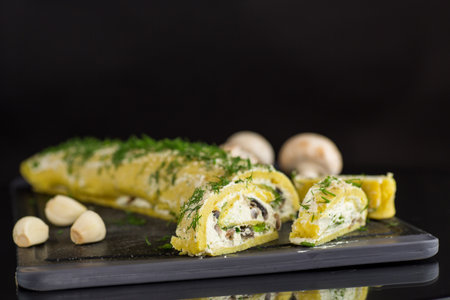 baked potato roll with cottage cheese filling with garlic and mushrooms, isolated on black background.の写真素材