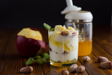 sweet homemade yogurt in a glass with apples, nuts and honey.の写真素材
