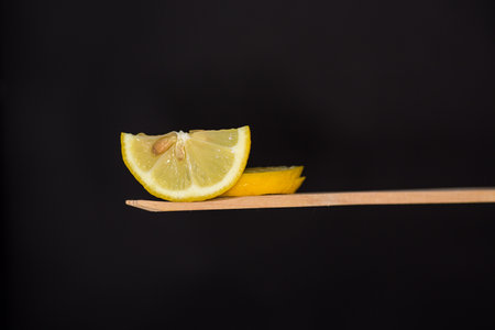slice of fresh juicy lemon on wooden spatula isolated on black background.の写真素材