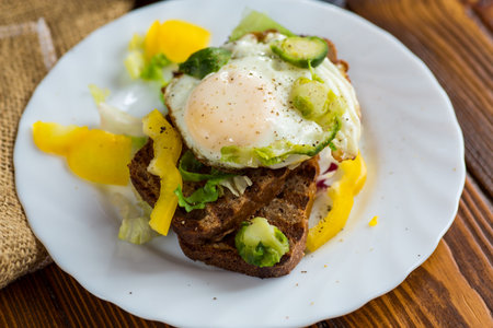 Egg on bread with vegetable garnish.の写真素材