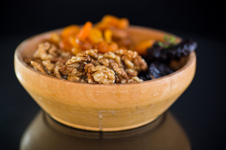 Prunes, dried apricots and nuts in a wooden bowl on a dark background.の写真素材