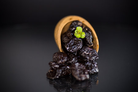 Prunes in a wooden spoon on a dark background.の写真素材