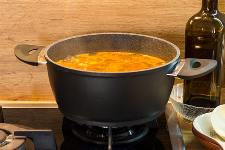 A pot of boiling soup on a gas stove.