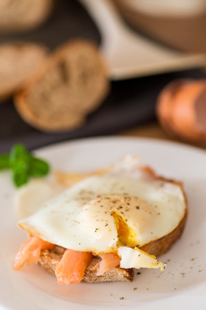 A slice of bread with lightly salted red fish and a cooked egg for breakfast.の写真素材