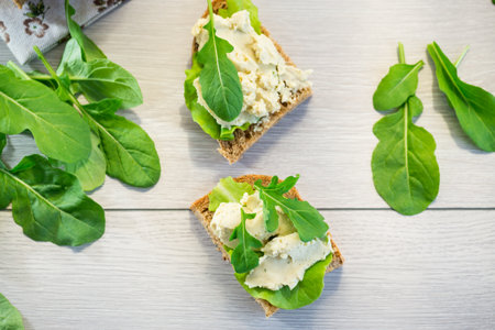 Appetizing sandwich with greens and fish spread on a light wooden table.の写真素材