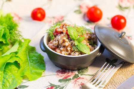 boiled buckwheat with vegetables in a ceramic bowl on a wooden table.の写真素材