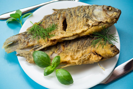 Appetizing fried crucian carp with butter and spices in a frying pan.