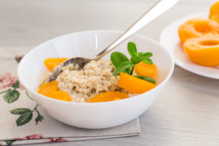 Nutritious milk porridge with pieces of sweet peaches.の写真素材