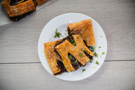 Golden puff pastries with sesame seeds, on a light wooden table.の写真素材