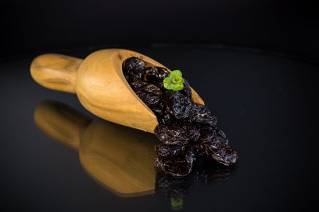 Prunes in a wooden spoon on a dark background.の写真素材