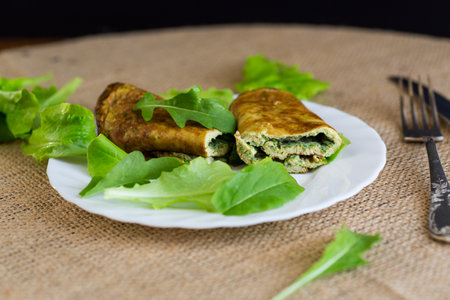 Omelette roll with greens and fresh arugula on a plate.の写真素材
