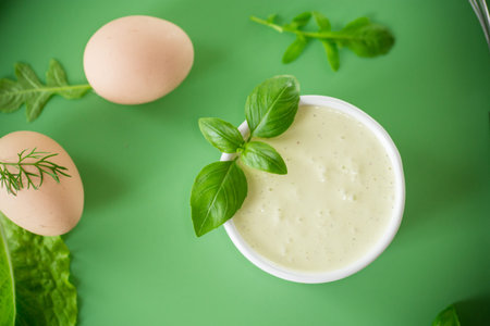 Top view of homemade mayonnaise with green herbs and eggs.