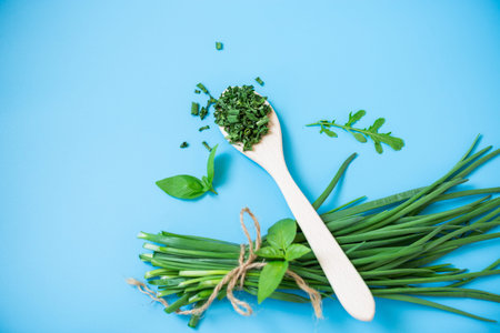 Top view of fresh green onions and herbs on blue background.