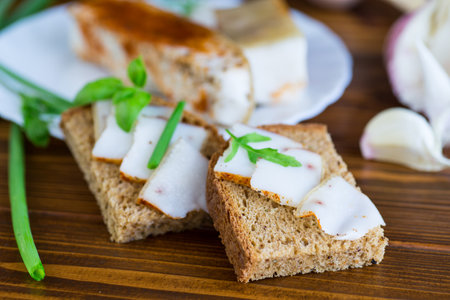 Traditional Ukrainian dish with lard and greens on a wooden table.の写真素材