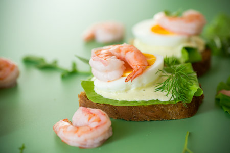 Appetizing breakfast with shrimp, egg and greens on top.の写真素材