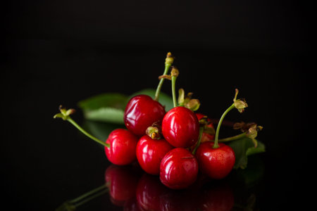 a handful of ripe red cherries on a black background.