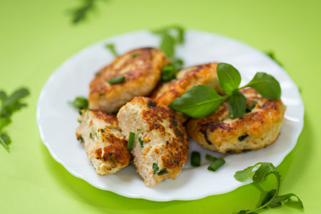 Homemade chicken cutlets on a plate isolated on a green background.の写真素材