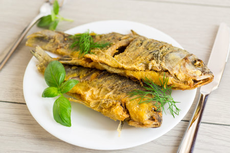 Homemade dish - golden crucian carp on a plate with spices.