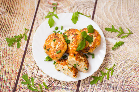view of chicken cutlets with herbs on wooden table.