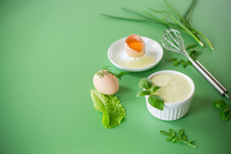 Homemade mayonnaise with herbs and eggs on a green background.の写真素材
