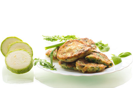 appetizing zucchini pancakes with green onions in a plate on a white background.の写真素材