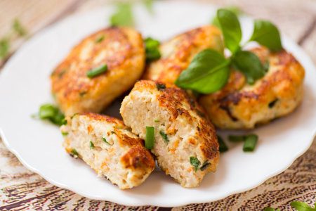 cooked chicken cutlets with herbs on a wooden table.