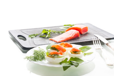 Egg halves with red salmon and herbs on a white background.