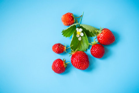 Ripe red strawberries on a blue background from above.