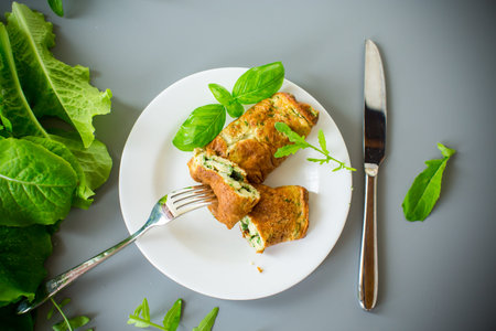Omelette roll with greens on top on a white plate.の写真素材