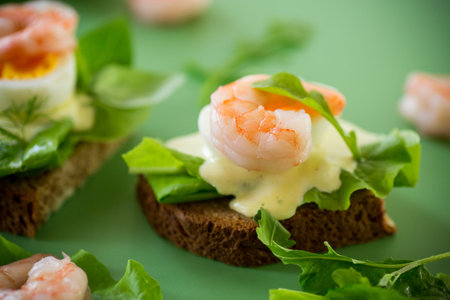 Light sandwich with seafood and greens on green background.の写真素材