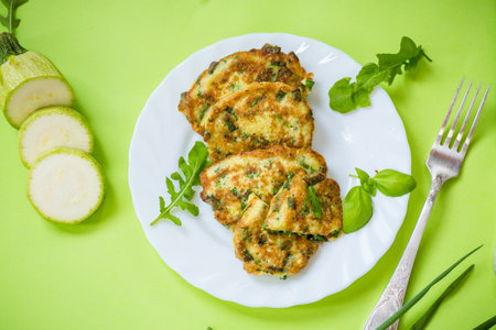 breakfast of zucchini pancakes with green onions in a plate on a green background.の写真素材