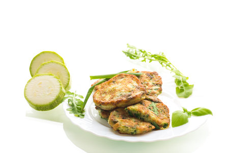 fried zucchini pancakes with green onions in a plate on a white background.の写真素材