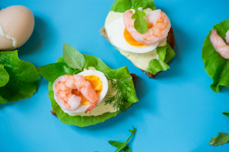 Sandwich with egg and shrimp on blue background from above.の写真素材