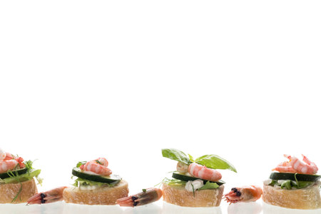 Minimalistic canapes with shrimps, salad and cucumber on a white background.の写真素材