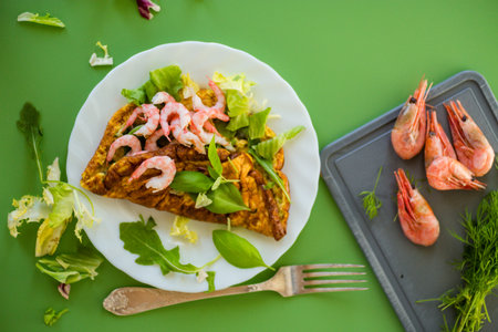Fried omelette with shrimps and greens on a green background.の写真素材