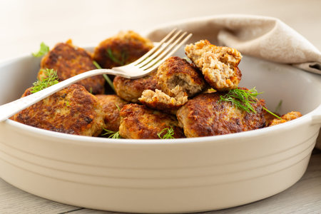 Delicious fried cutlets in a baking dish on a white table.