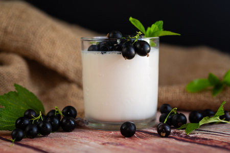 Blackcurrant and homemade yogurt in a transparent glass on a wooden.の写真素材