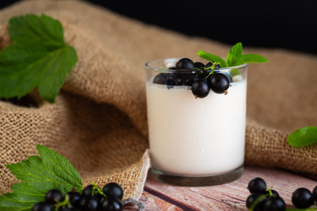 Fresh healthy breakfast of yogurt and blackcurrant berries on a wooden.