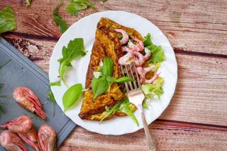 Delicious omelette with shrimps and fresh greens on top.