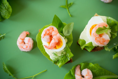 Appetizing breakfast with shrimp, egg and greens on top.