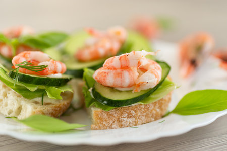 Appetizing appetizers with shrimps, sauce and cucumbers on a wooden table.の写真素材