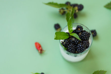 Summer yogurt with black blackberries and drops on glass.