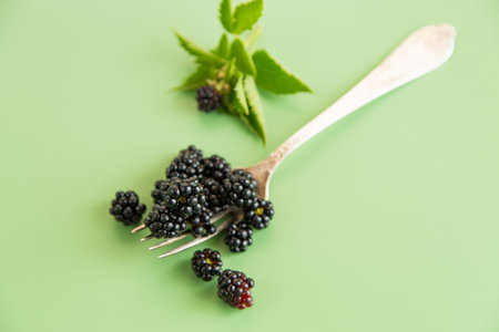 Black blackberries with greenery, top view.