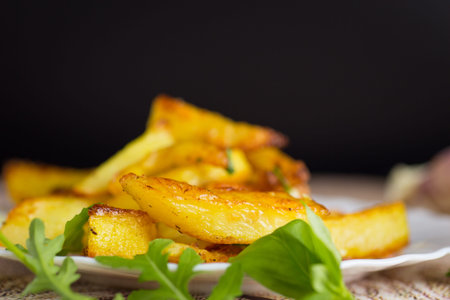 Delicious potatoes with a crispy crust for dinner on a black background.